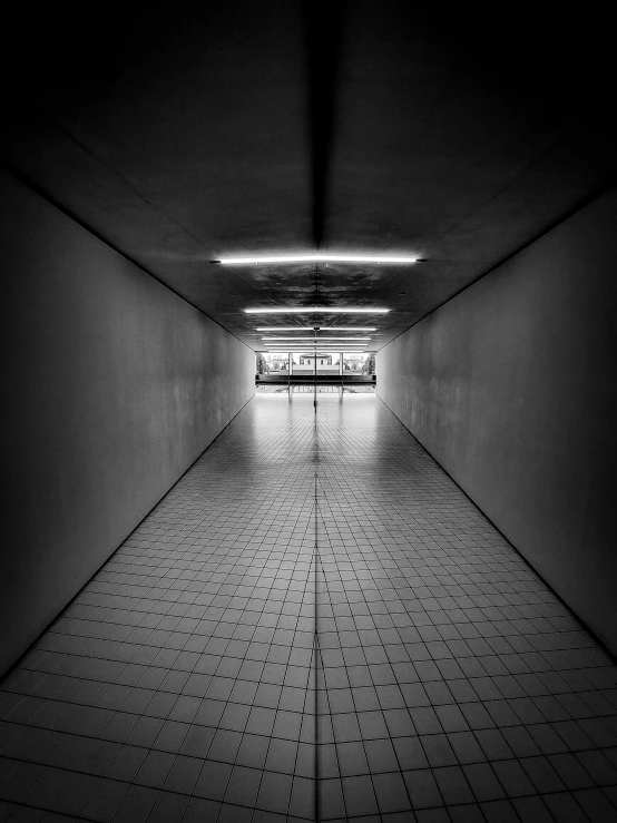 a black and white image of an empty hallway with light coming through