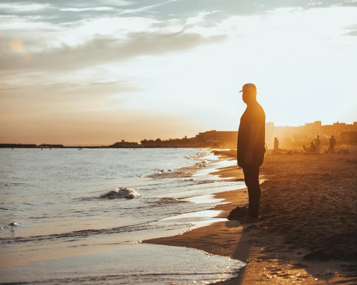 a man in a hoodie standing by the ocean