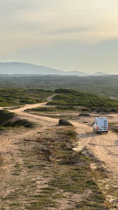 a van driving across a dirt road in the middle of nowhere