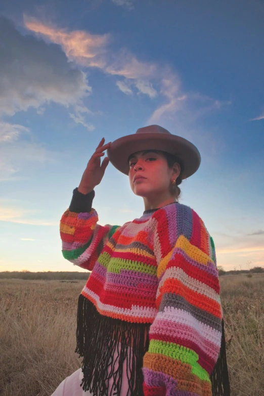 woman in a rainbow colored shawl with a hat on her head