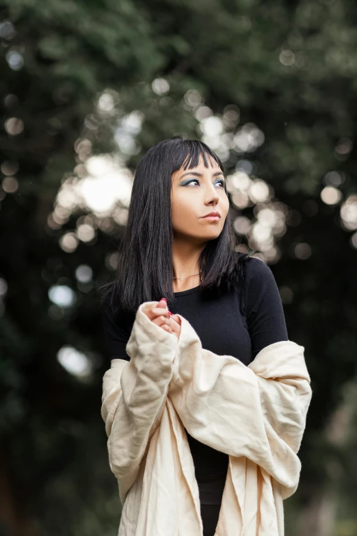 a girl that is wearing a coat is standing with her arms folded