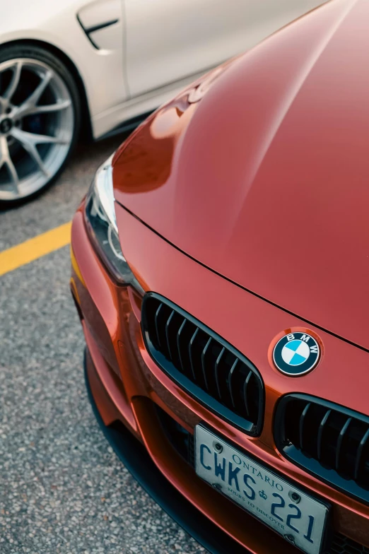 a bmw car parked next to another red car