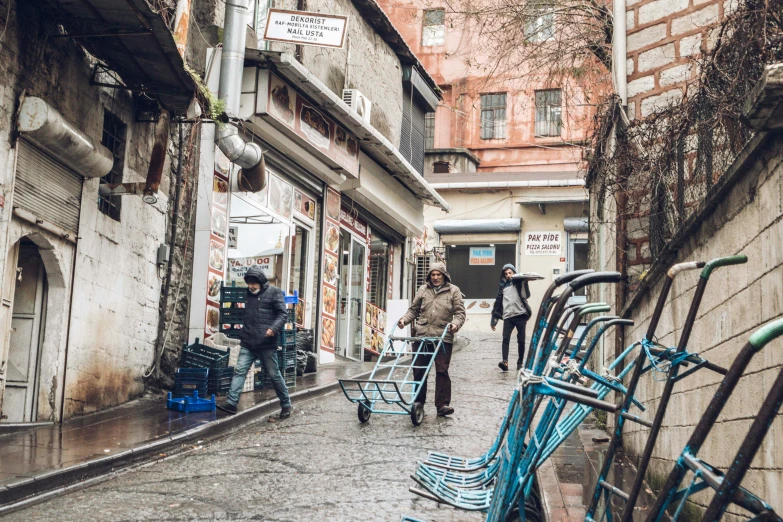 several people walking down an old narrow alley with blue bikes