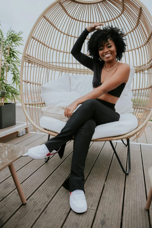 a beautiful young woman sitting on a chair on a patio