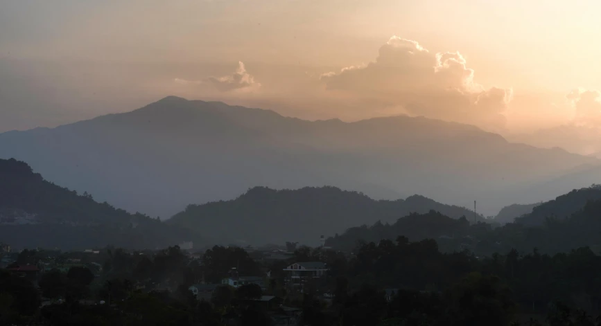 mountains and trees at dusk with sun behind them