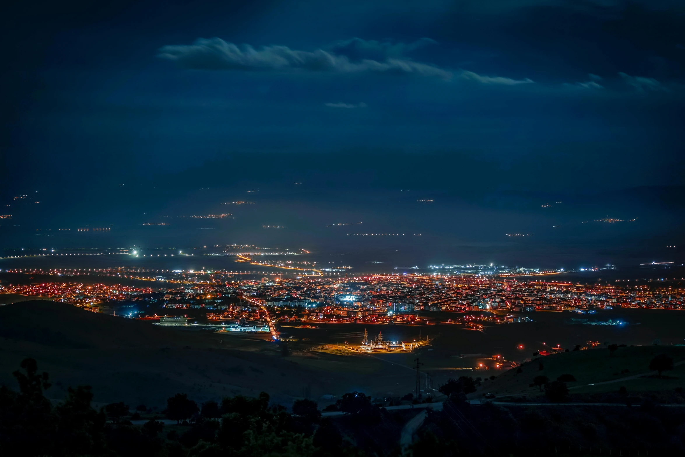 a night time view of a town and the moon lit sky