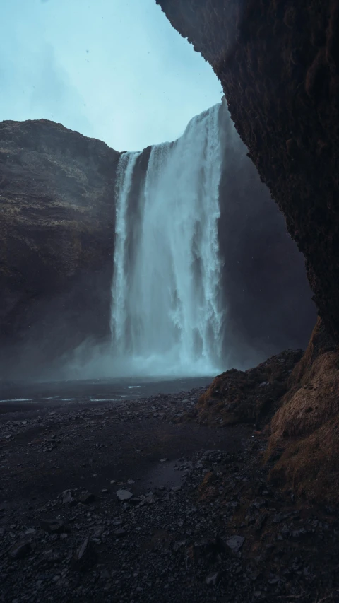 a man standing on the bottom of a waterfall while looking at a camera