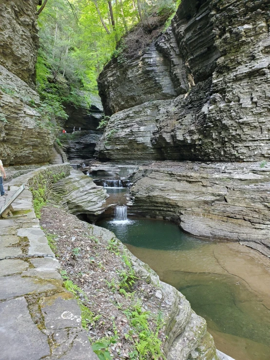 the boy walks on the trail along a waterfall