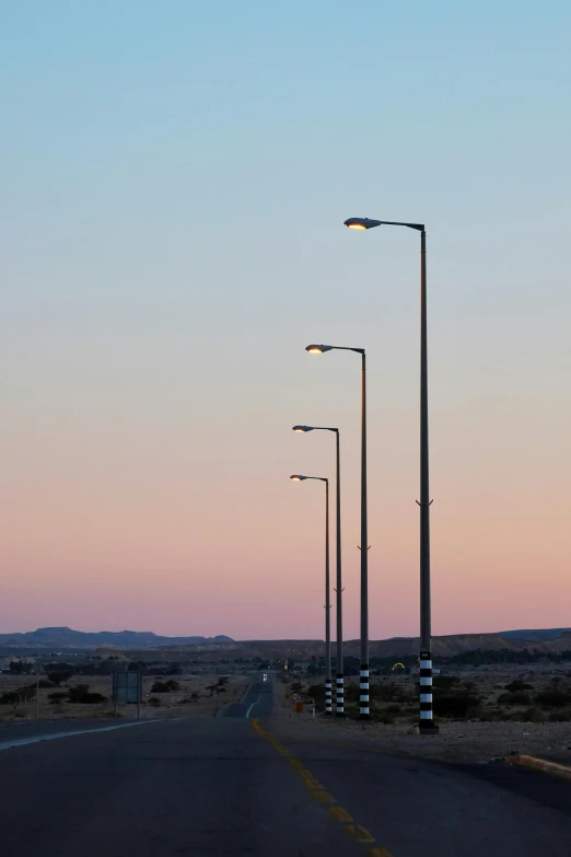 a highway with street lamps in the middle at dusk