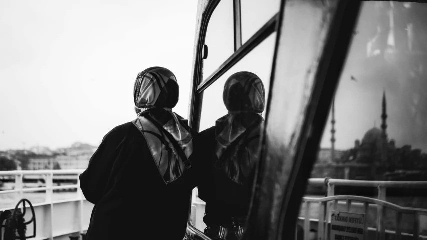 two people looking out of a window at a boat