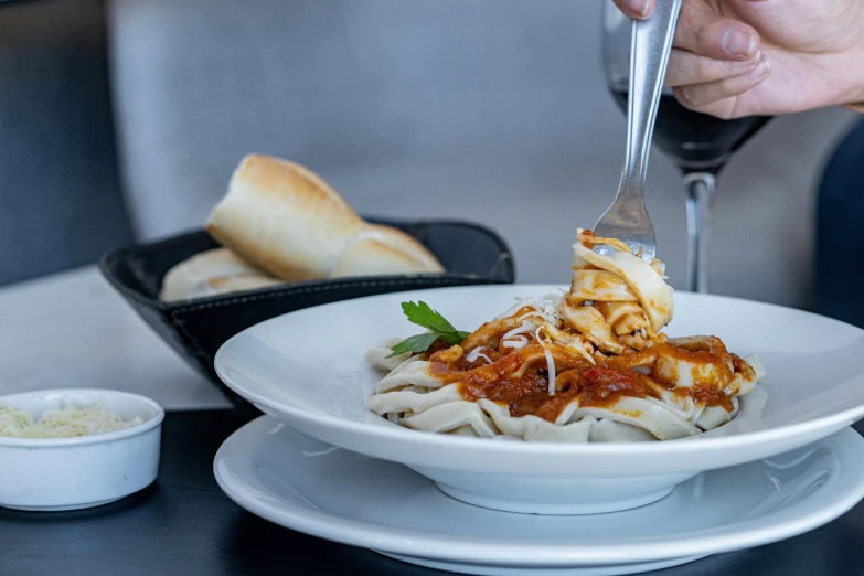 someone is holding a fork and spoon over a dish with pasta on a plate