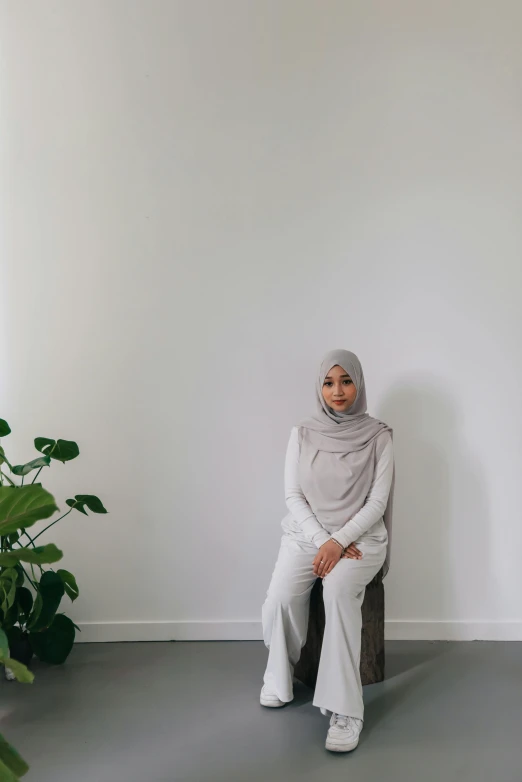 a woman in grey scarf sitting on a stool