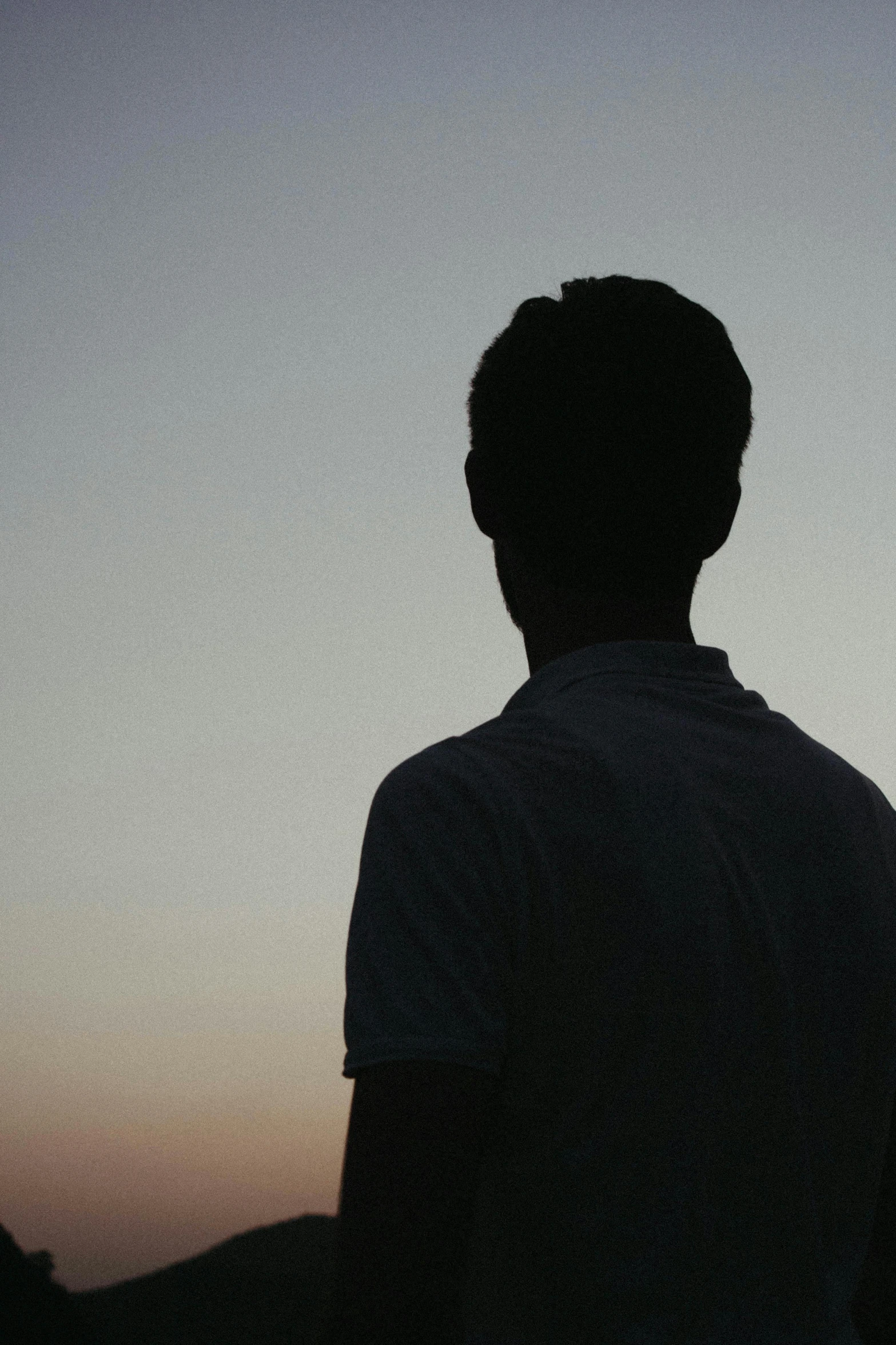 the silhouette of the back of a man's head against a blue sky