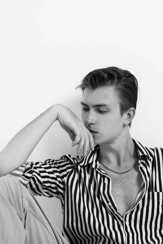 a young man sitting on top of a couch in a striped shirt
