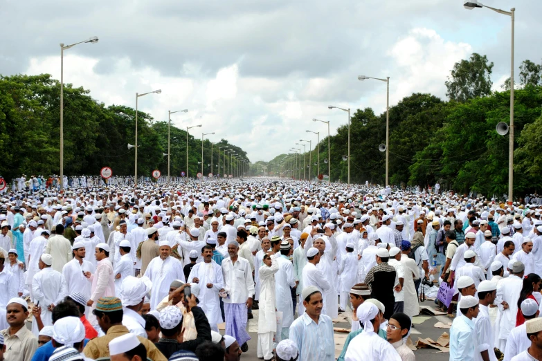 a large group of people wearing white and standing in the middle of a road