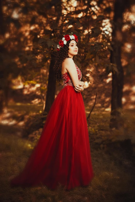 the young lady in a red dress is standing in the woods