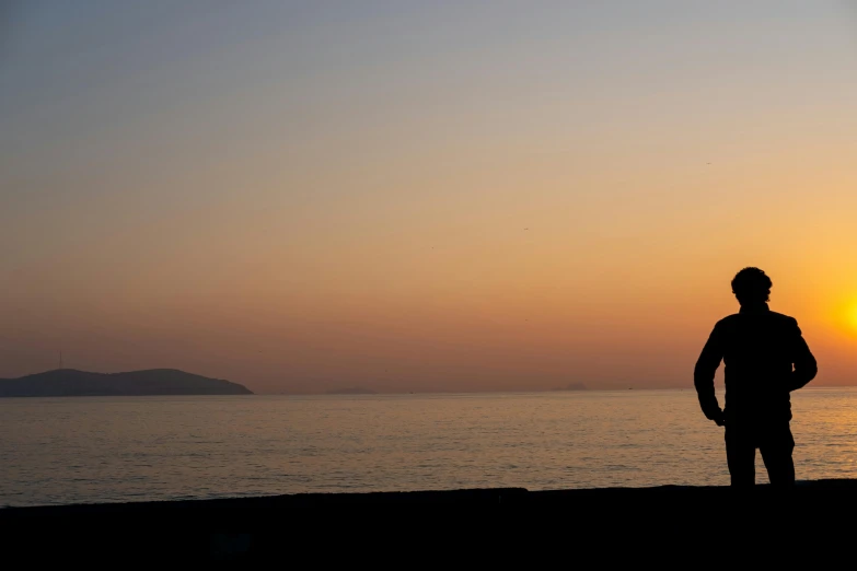 man standing on beach watching the sun set