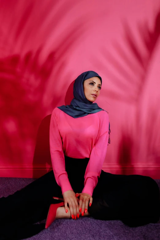 a woman wearing hijab sitting on a floor with her hand in the middle