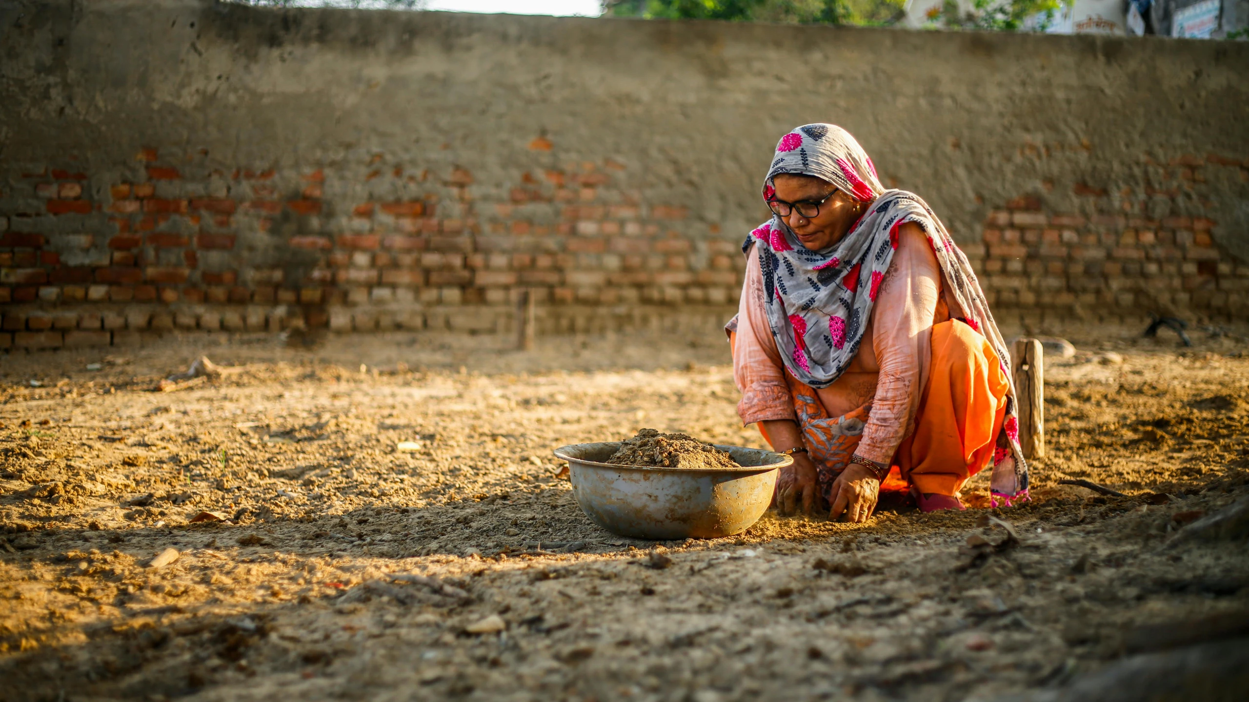 an indian woman in orange and white holding a bowl of food