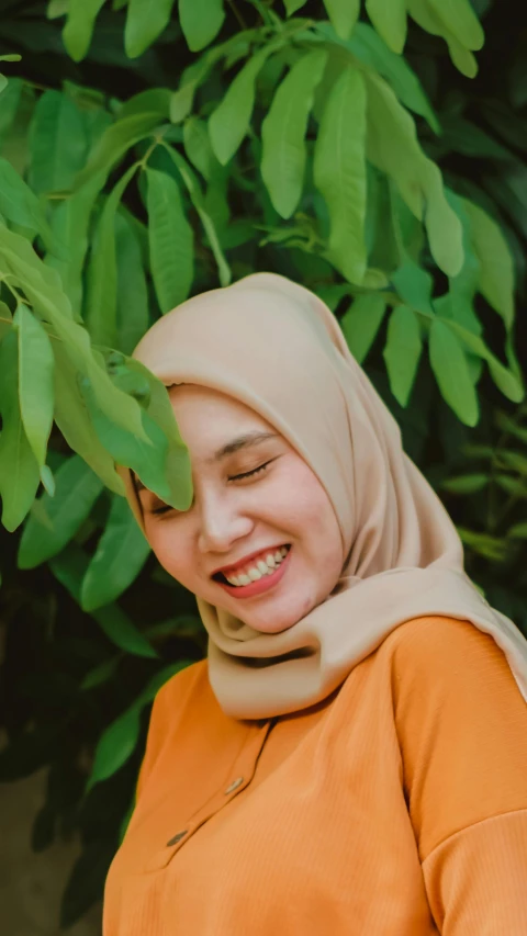 a woman smiling underneath a green tree