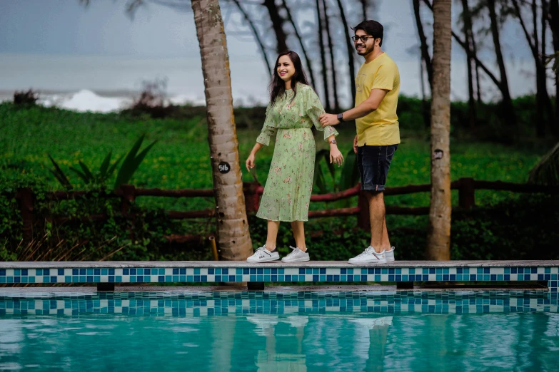 a couple stands next to a pool with trees