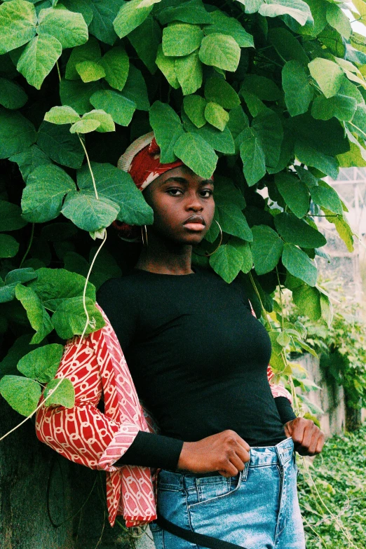 the woman wearing the bag is standing by the tree