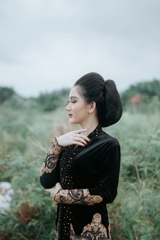 a woman in black dress standing in front of trees