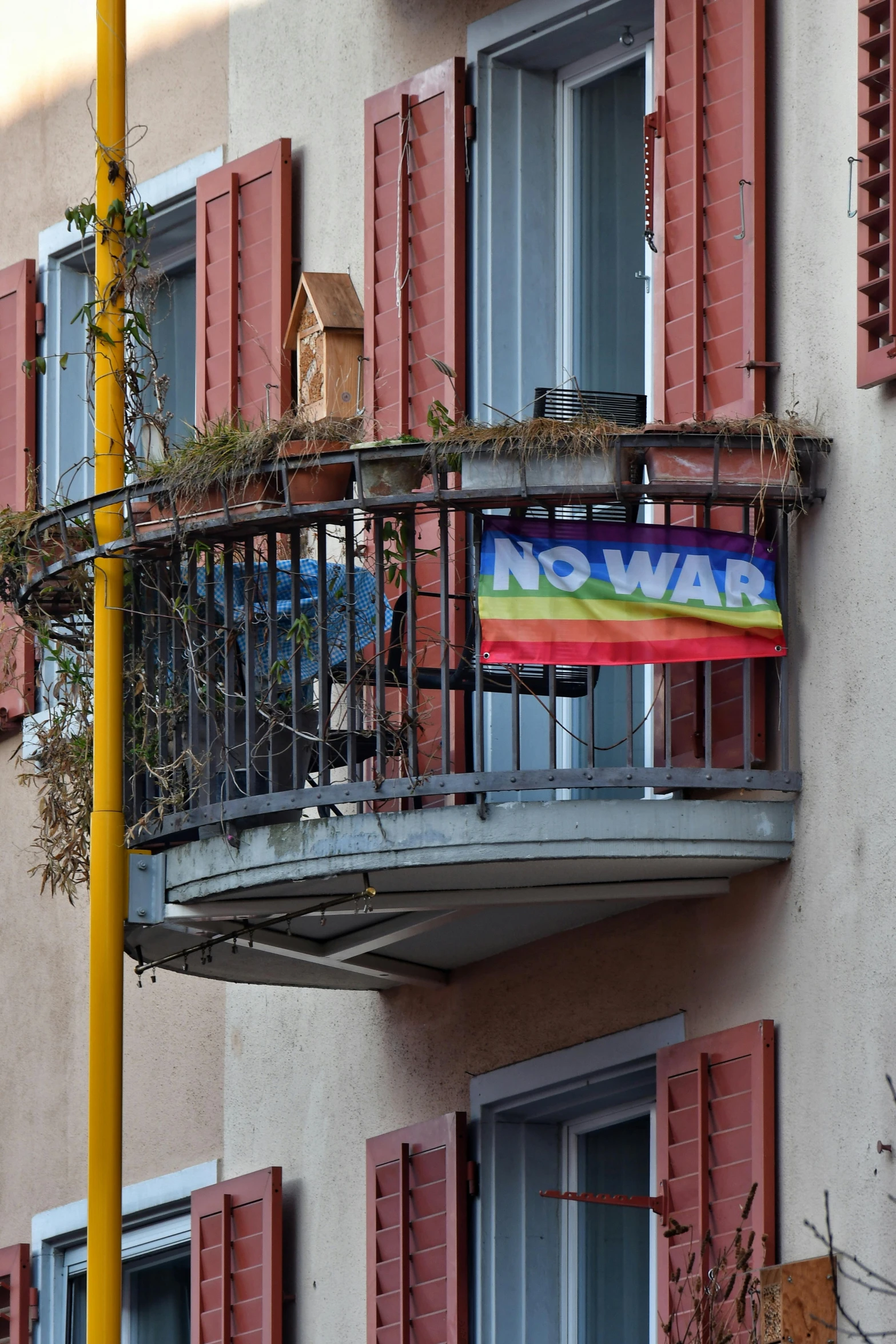 a balcony with red shutters and windows that have a rainbow flag on it