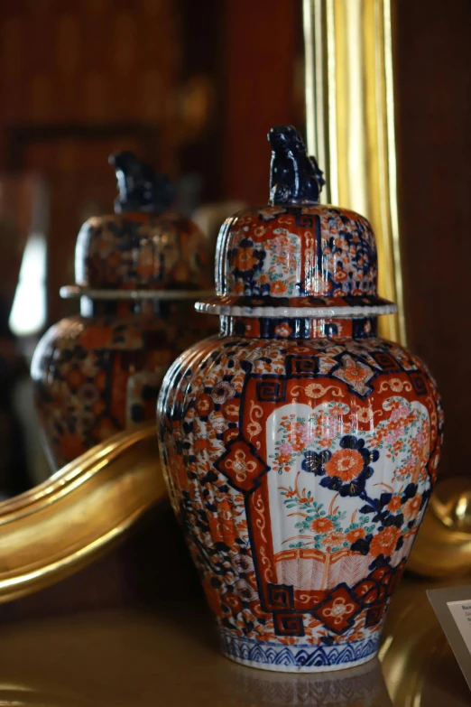 a red and blue flower pattern urn in front of a mirror