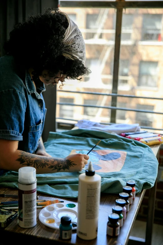 a woman is painting some flowers on a shirt