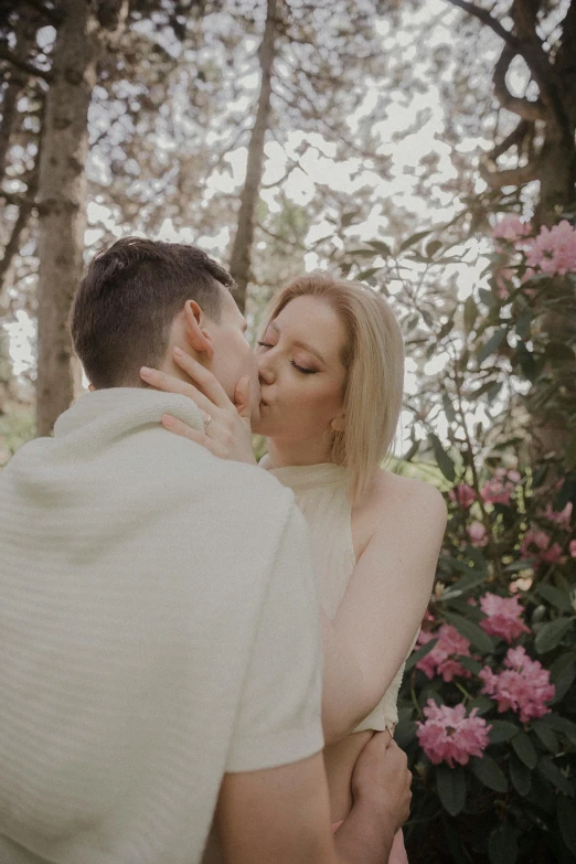 a couple kissing in front of pink flowers