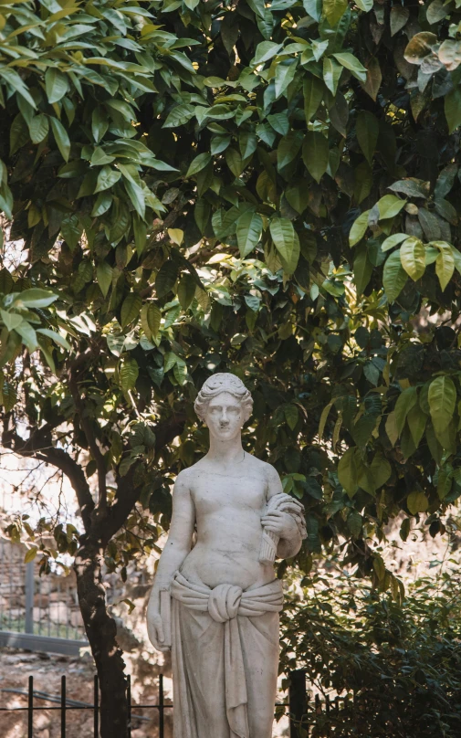 a statue in the shape of a woman is next to some trees