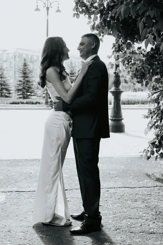 a young man and woman in formal wear stand next to each other on a stone walkway