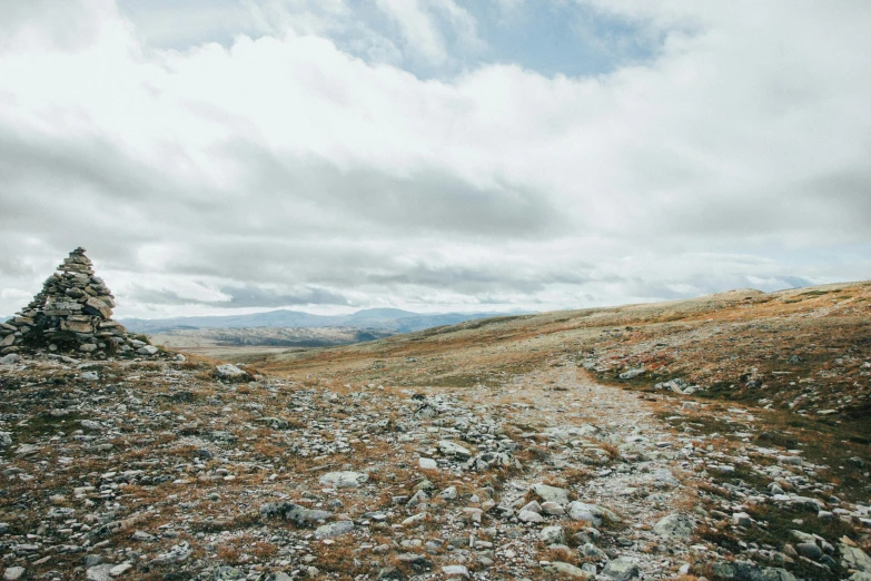 a lone hiker trekking up a hill towards a rock formation