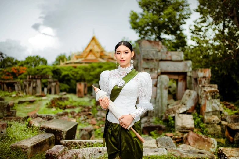 a beautiful woman with a green ribbon is standing in an old cemetery