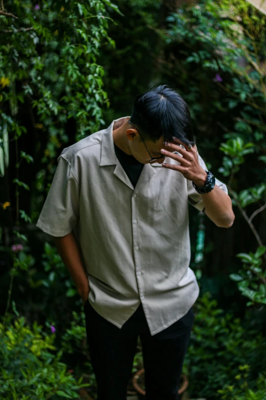 an asian man is walking in front of green plants