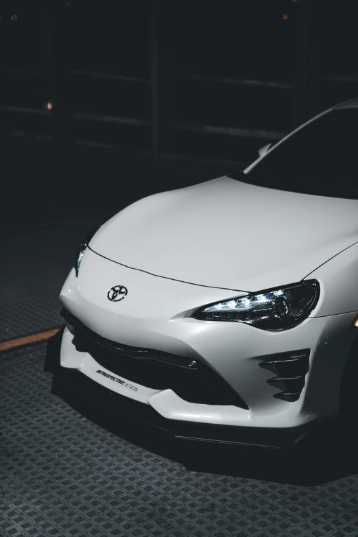 the front end of a white car in a dimly lit room