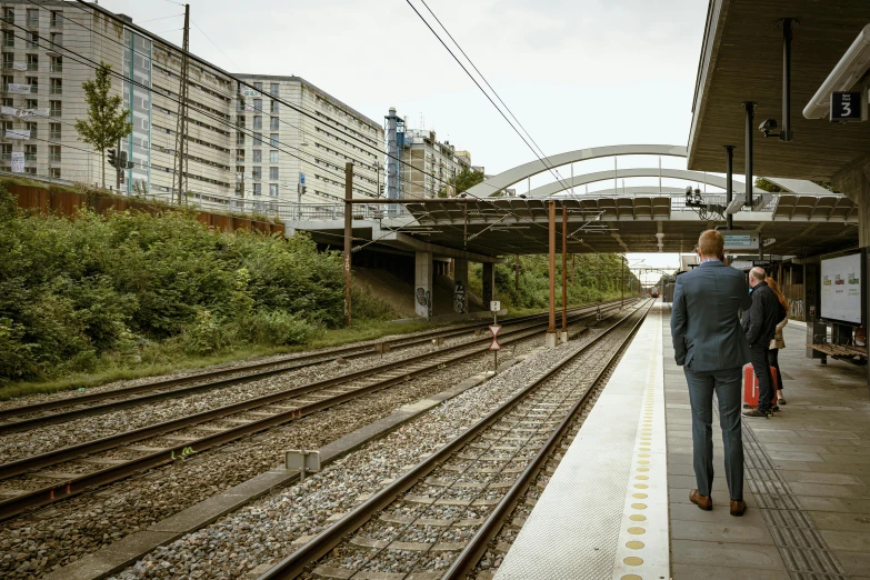 man standing by train tracks as others stand nearby