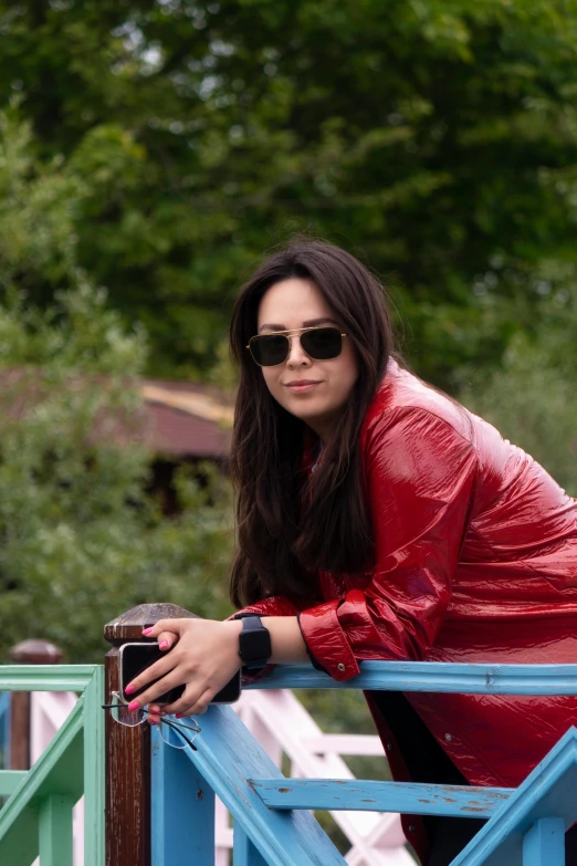 a woman with sunglasses leaning on a rail next to trees