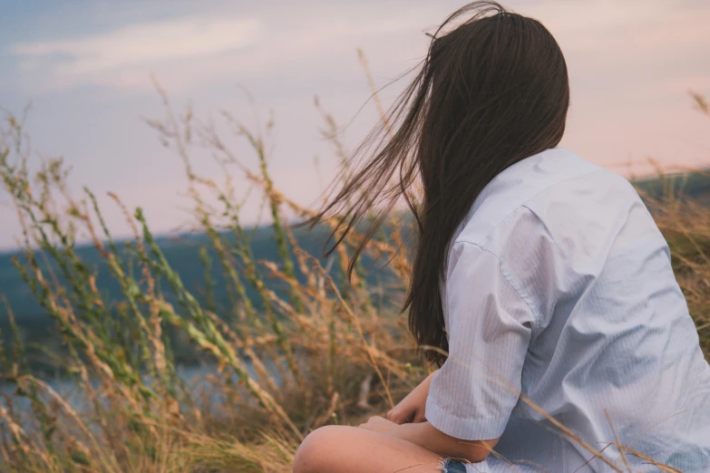 the back view of a woman sitting by some bushes