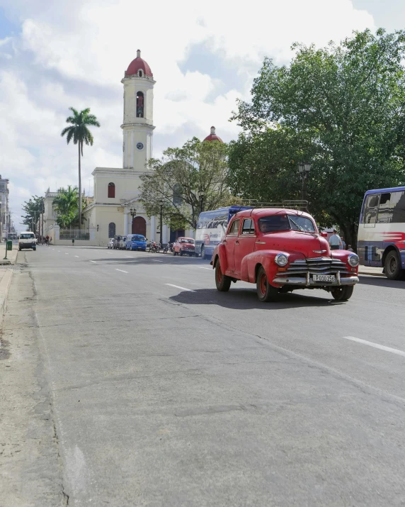 a red car parked on the side of a road next to a truck