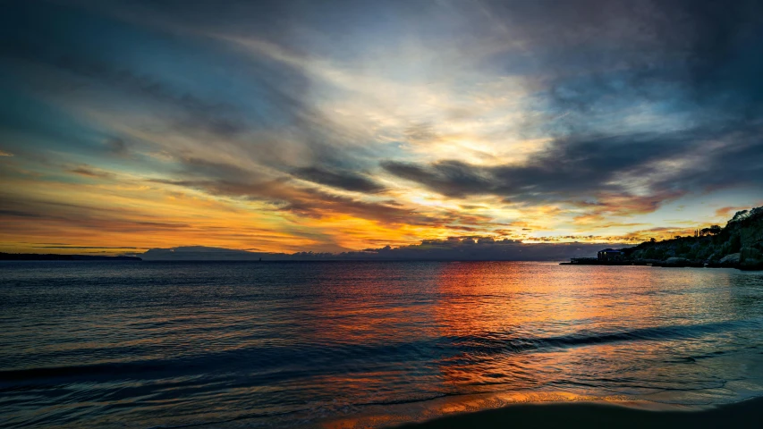 a beach with a lone surfer at sunset