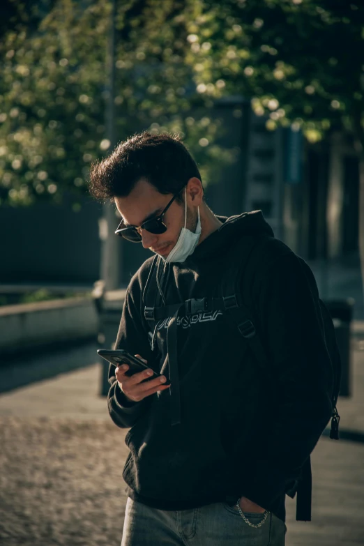 a man in black jacket and sunglasses holding a smart phone