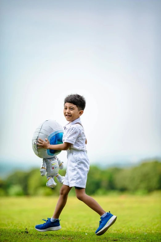 a little boy carrying some soccer balls in the field