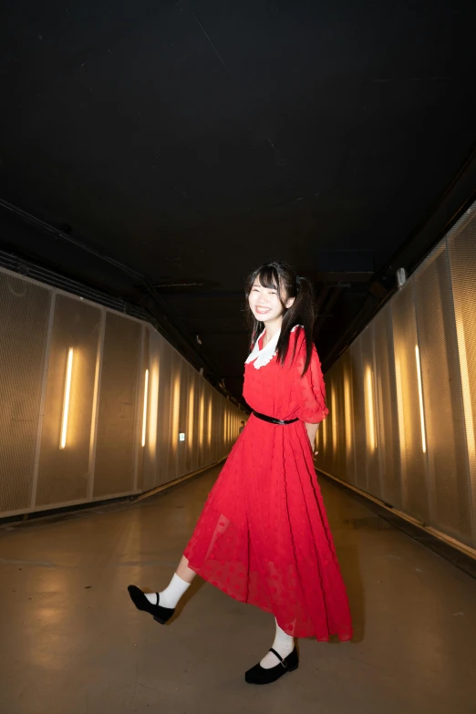 a woman in red dress walking across the tunnel