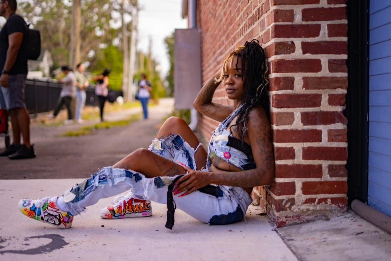 a woman with dreadlocks and sneakers sitting on the curb