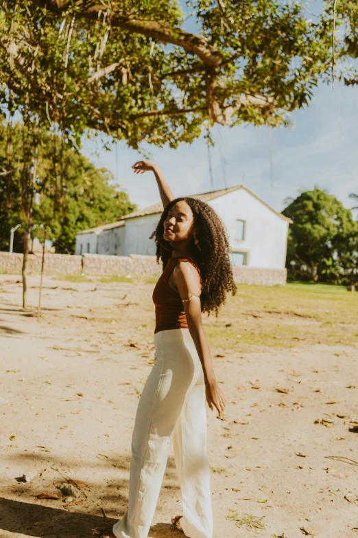 a woman standing in the dirt next to a tree