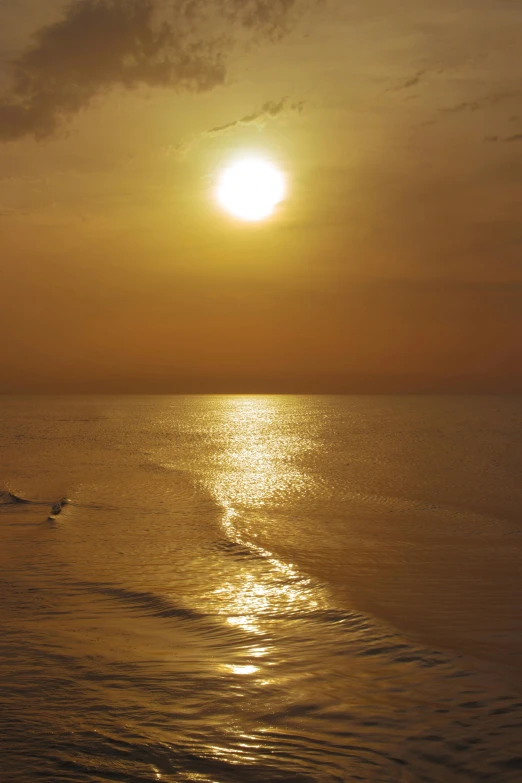 a sunset on a lake with the sun setting and waves