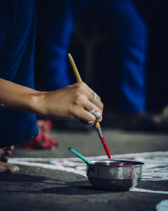 a person holding scissors near a pot with paint