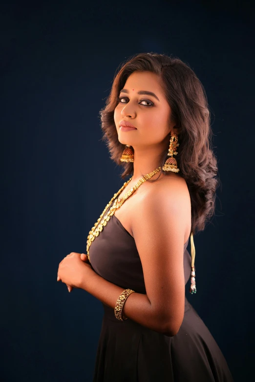 a young woman posing for a pograph in a dress and jewelry